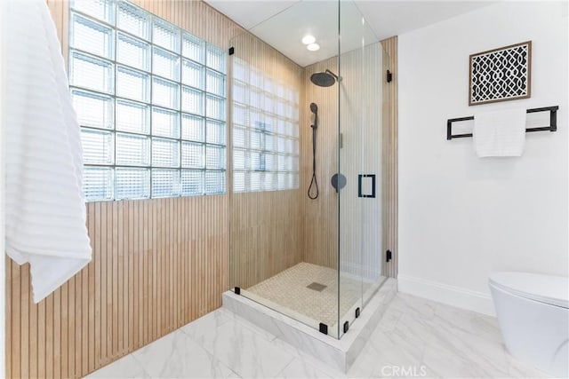 bathroom with walk in shower, toilet, plenty of natural light, and wood walls