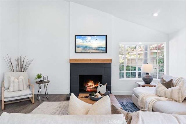 living room with a tile fireplace, dark hardwood / wood-style floors, and lofted ceiling