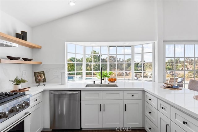 kitchen featuring backsplash, stainless steel appliances, vaulted ceiling, sink, and white cabinets