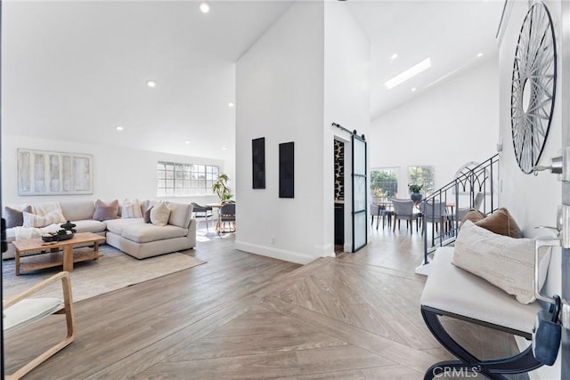 living room featuring a barn door, a wealth of natural light, light parquet floors, and high vaulted ceiling