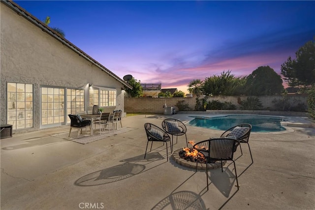 pool at dusk with a patio and a fire pit