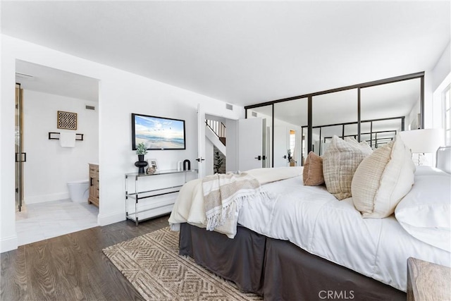 bedroom with hardwood / wood-style floors and ensuite bath