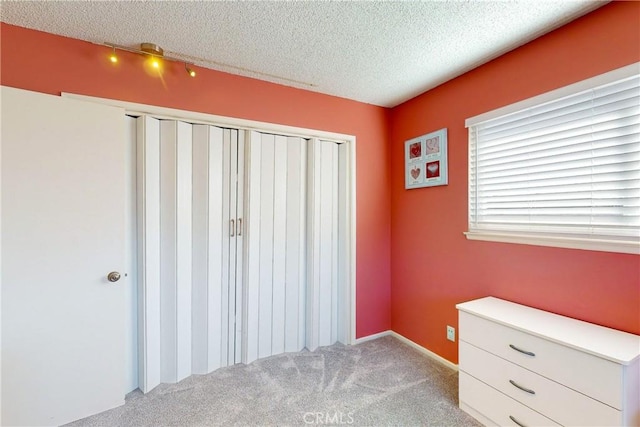 unfurnished bedroom with carpet, a textured ceiling, and a closet