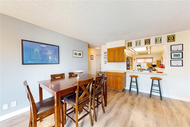 dining area featuring light wood-type flooring and a textured ceiling