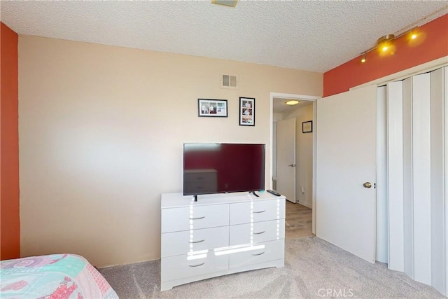 bedroom with a textured ceiling and light colored carpet