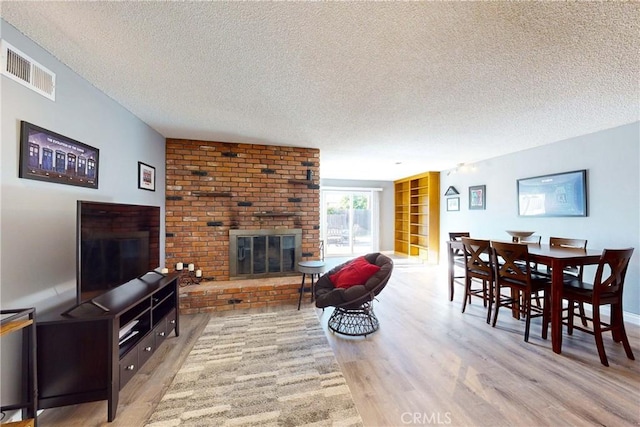 living room with a fireplace, a textured ceiling, and light hardwood / wood-style floors