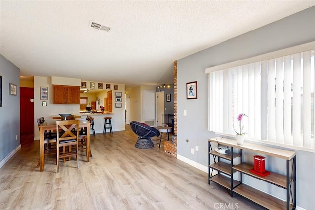 dining area with a textured ceiling and light hardwood / wood-style flooring