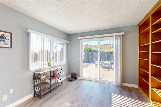 doorway with light hardwood / wood-style floors and a textured ceiling