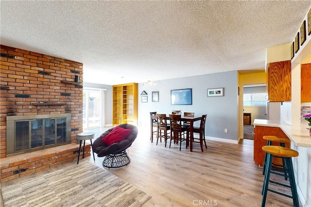 dining room featuring a fireplace, a textured ceiling, and light wood-type flooring