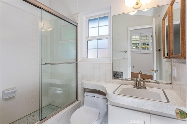 bathroom featuring vanity, toilet, a shower with door, and decorative backsplash