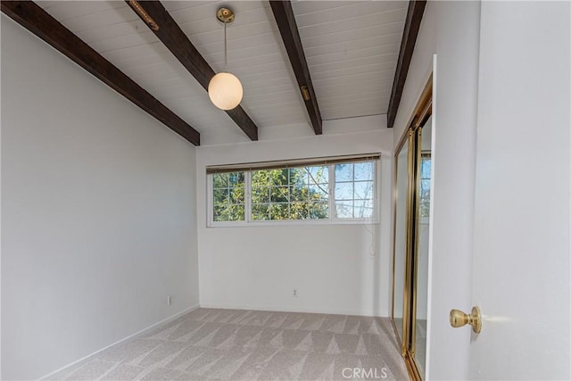 spare room featuring vaulted ceiling with beams and light colored carpet