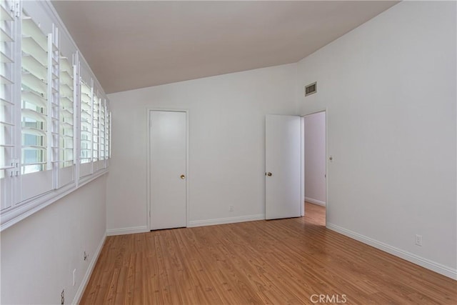 unfurnished bedroom featuring lofted ceiling and light wood-type flooring