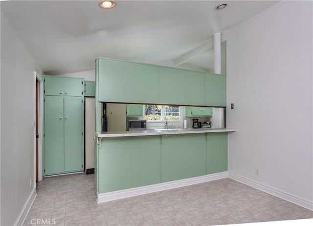 kitchen featuring kitchen peninsula, vaulted ceiling, and green cabinetry