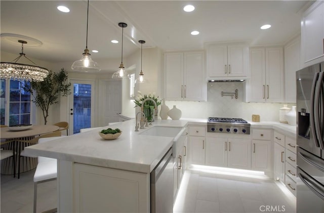 kitchen with sink, white cabinets, stainless steel appliances, and a notable chandelier