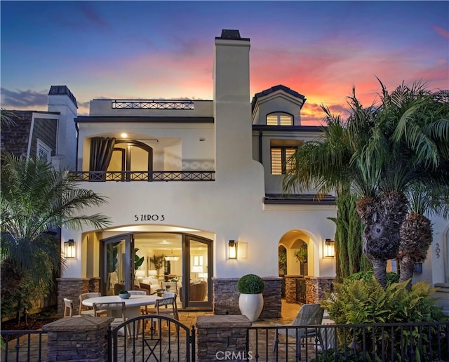 back house at dusk featuring a patio