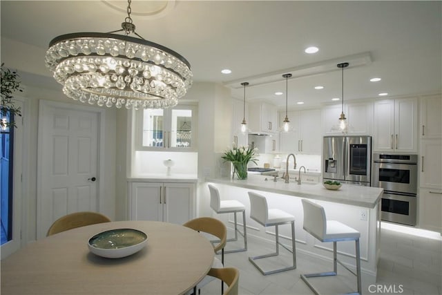 kitchen featuring hanging light fixtures, a notable chandelier, a kitchen bar, white cabinets, and appliances with stainless steel finishes