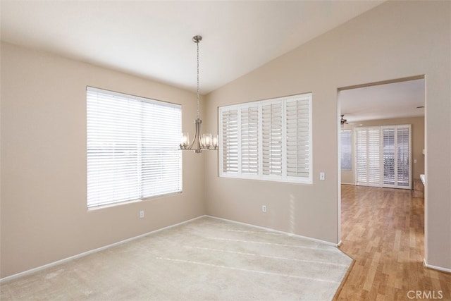 spare room featuring a chandelier, vaulted ceiling, and baseboards