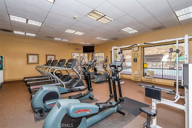 exercise room with baseboards and a drop ceiling