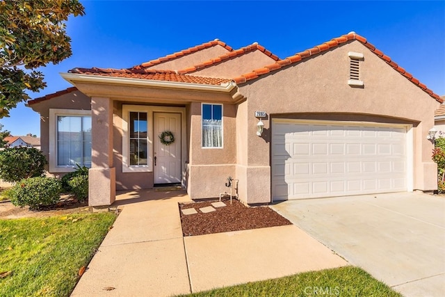 mediterranean / spanish home featuring concrete driveway, a tile roof, an attached garage, and stucco siding