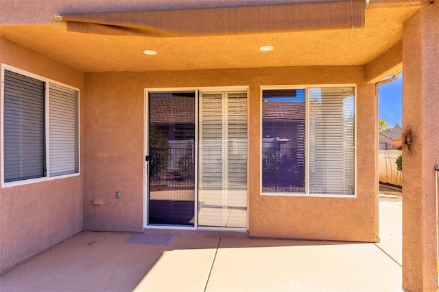 entrance to property with a patio and stucco siding