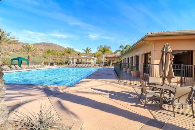 pool with a mountain view, fence, and a patio