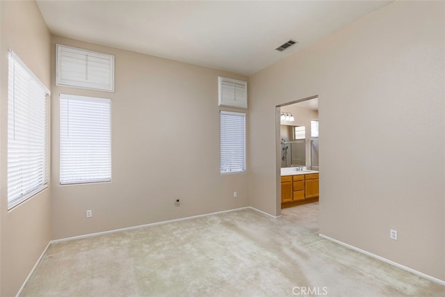 unfurnished bedroom featuring light colored carpet, visible vents, a sink, and baseboards