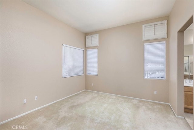 unfurnished room featuring light colored carpet and baseboards