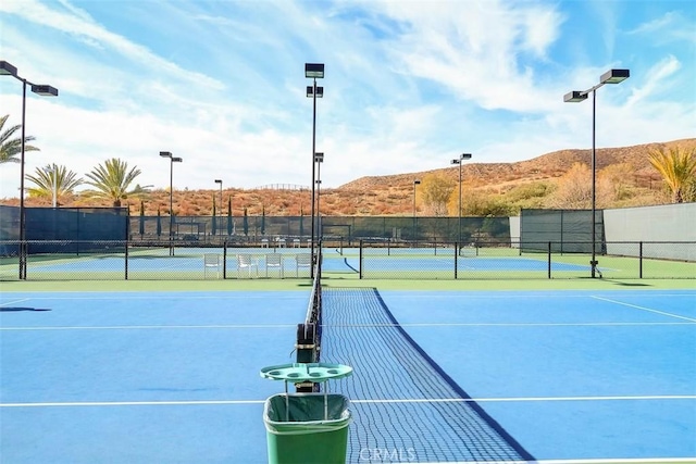 view of sport court with a mountain view and fence