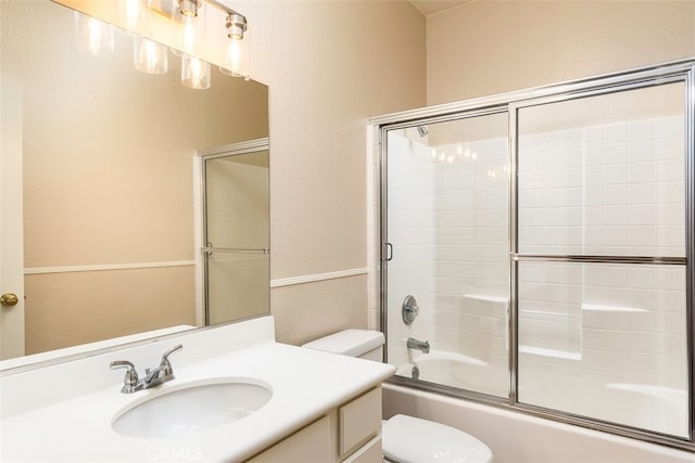 bathroom with combined bath / shower with glass door, vanity, and toilet