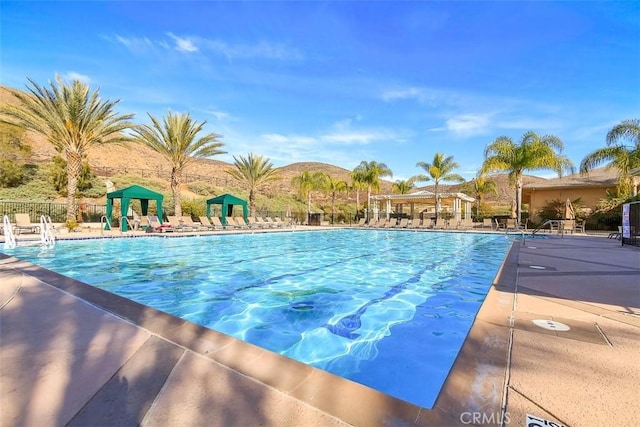 pool with fence, a mountain view, and a gazebo