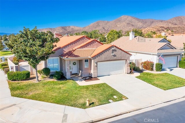 view of front of house with a front yard, a garage, and a mountain view