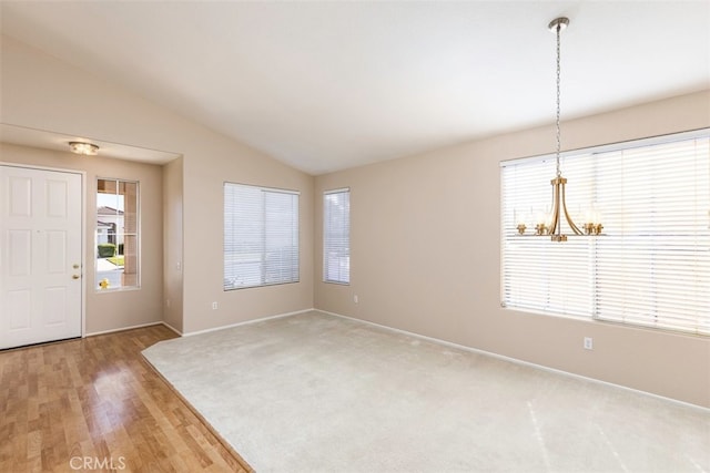 entrance foyer featuring lofted ceiling, an inviting chandelier, baseboards, and wood finished floors