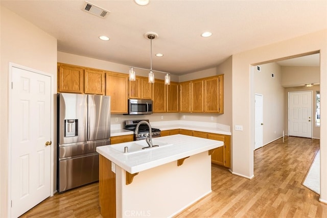 kitchen with a kitchen island with sink, stainless steel appliances, visible vents, a kitchen bar, and pendant lighting