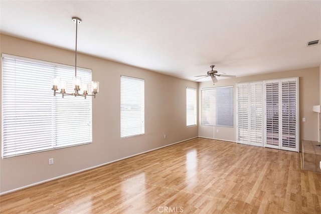 unfurnished room with ceiling fan with notable chandelier, wood finished floors, and visible vents