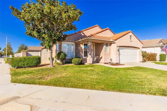 mediterranean / spanish-style home featuring a front yard and a garage