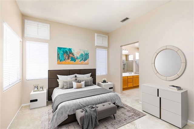 bedroom with baseboards, connected bathroom, visible vents, and light colored carpet