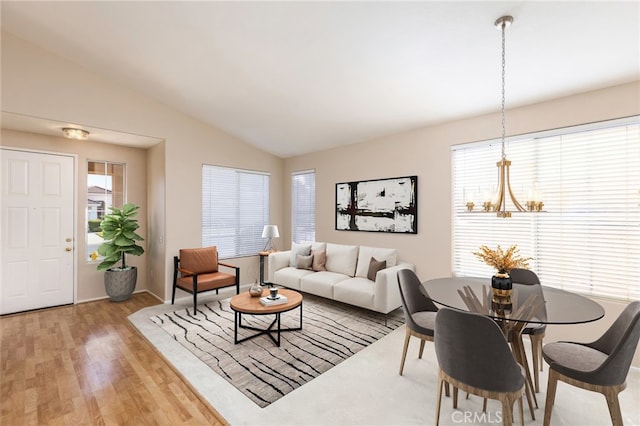 living area with lofted ceiling, light wood-style floors, and a notable chandelier