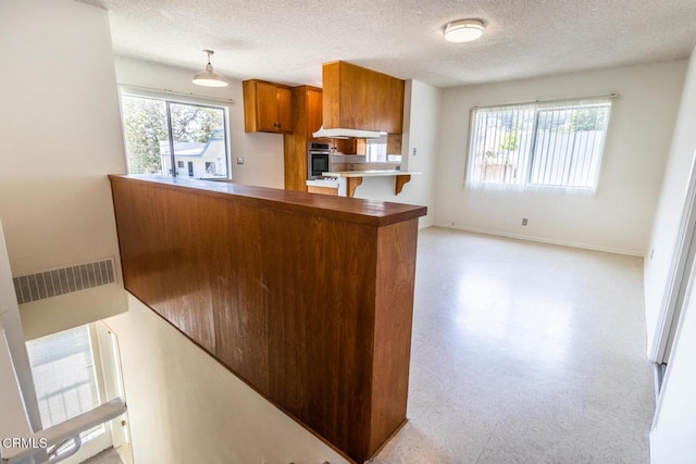 kitchen with kitchen peninsula, a textured ceiling, plenty of natural light, and hanging light fixtures