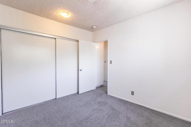 unfurnished bedroom featuring carpet, a textured ceiling, and a closet