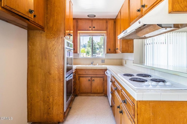 kitchen featuring white electric cooktop, tile counters, and sink