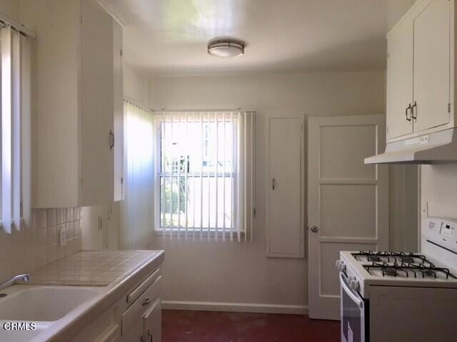 kitchen featuring tile countertops, white cabinets, sink, decorative backsplash, and gas range gas stove