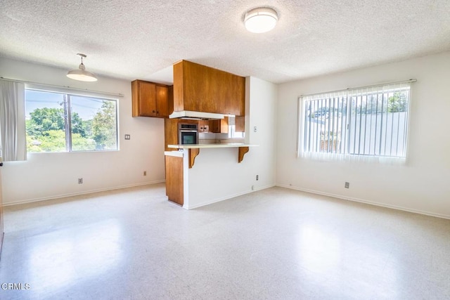 kitchen with a breakfast bar, oven, hanging light fixtures, and a textured ceiling