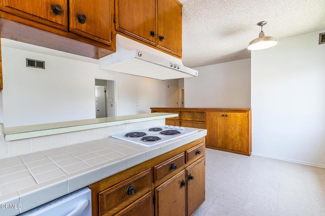 kitchen with a textured ceiling, tile countertops, white electric stovetop, and decorative light fixtures