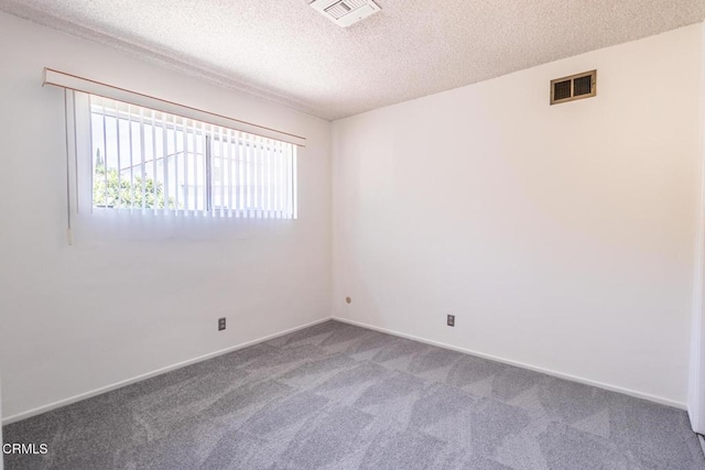 carpeted empty room with a textured ceiling