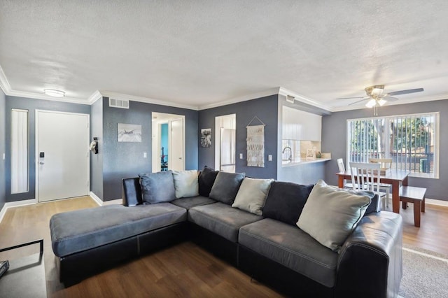 living room with ceiling fan, hardwood / wood-style floors, a textured ceiling, and ornamental molding