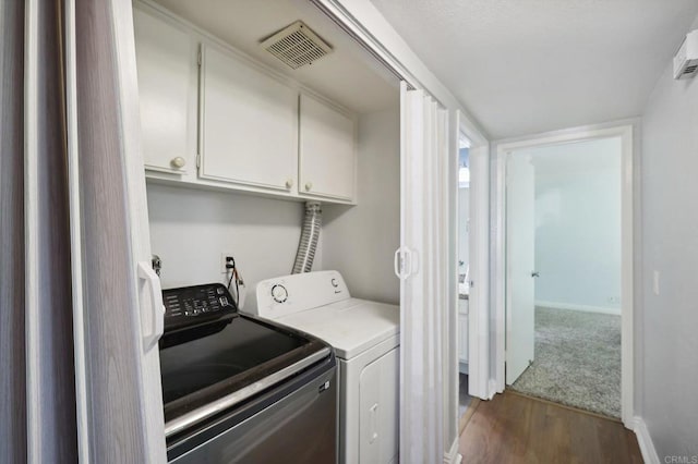 laundry room featuring washing machine and dryer, dark wood-type flooring, and cabinets