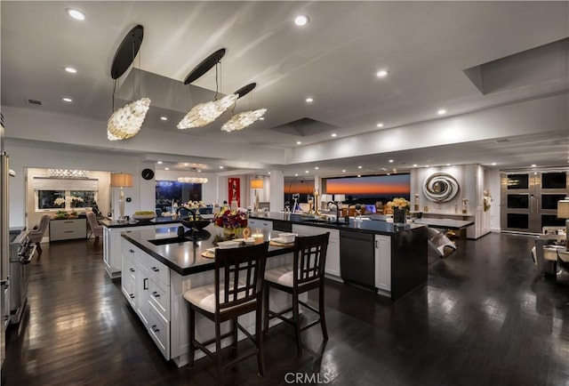 kitchen with white cabinetry, dishwasher, hanging light fixtures, a breakfast bar, and a center island with sink