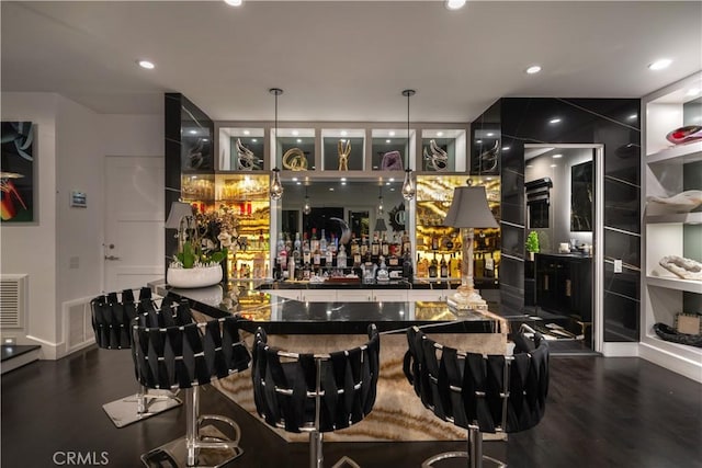 bar with built in shelves, hanging light fixtures, and dark wood-type flooring