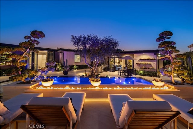 pool at dusk with a patio area