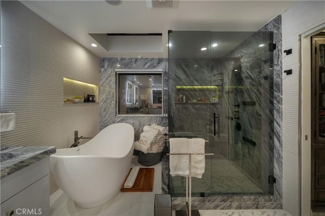 bathroom with vanity, shower with separate bathtub, and tile walls